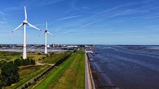 Aerial view of the Volkswagenwerk Emden factory with wind turbines and the Ems river estuary in Emden, Niedersachsen, Germany.