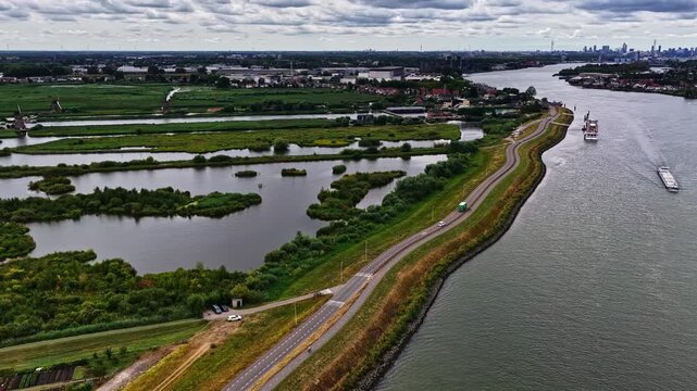 Aerial view of the historic Kinderdijk windmills, a UNESCO World Heritage site, situated along the river with green polders and a barge in Kinderdijk, Zuid-Holland, Netherlands.
