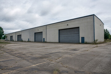 Fototapeta premium Closed industrial building with empty parking lot, unemployment and economic downturn concept