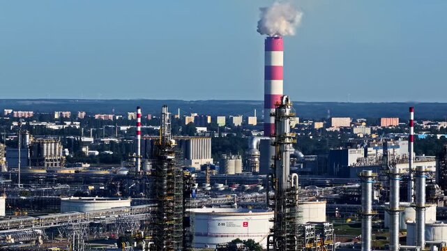 Aerial view of the Orlen Plock Production Plant with industrial towers, storage tanks, and smoke rising from a chimney in Plock, Masovian Voivodeship, Poland.