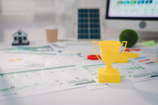esg concept, Yellow trophy cup on financial document at office desk suggesting business achievement, success, competition, reward, and positive performance in professional workplace setting