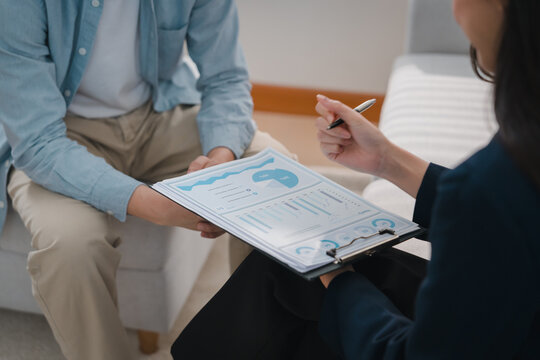 Financial advisor discussing wealth planning with client through detailed report and pen in professional consultation, creating focused business conversation
