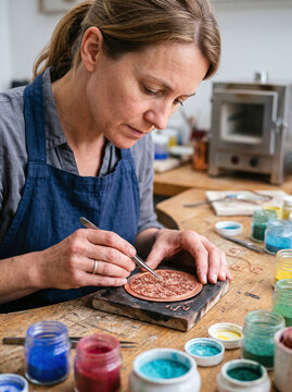 Artisan woman crafting intricate cloisonne enamel artwork with wire in workshop