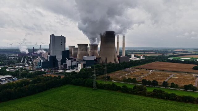 Aerial view of RWE Power AG power plant Niederaussem with cooling towers emitting steam over agricultural fields in Bergheim, Nordrhein-Westfalen, Germany.
