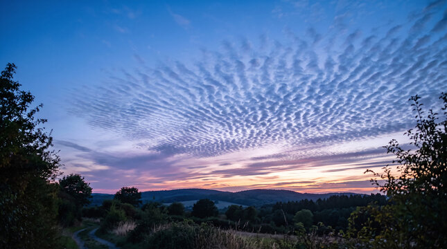 Scenic mackerel sky with rippling clouds over rolling hills at sunset dusk