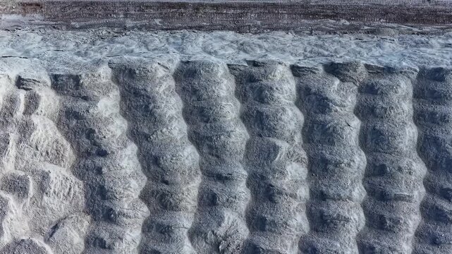 Aerial view of the textured surface of an excavated quarry with deep vertical ridges and layered soil patterns in Kedainiai, Kaunas County, Lithuania.