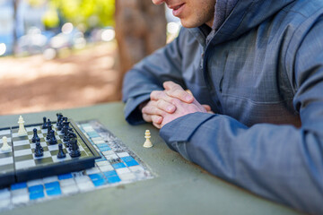 Man playing chess outdoors in park concentrating on game © Uriel Lu Photo