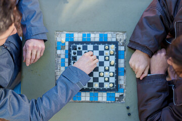 People playing chess outdoors on a public table © Uriel Lu Photo