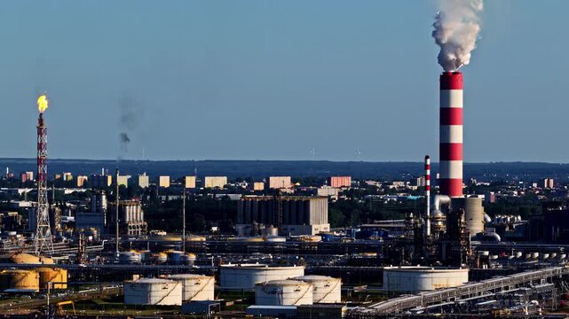 Aerial view of Orlen Plock Production Plant with its iconic red and white striped chimney, flare stack, and storage tanks in Plock, Mazowieckie, Poland.