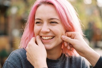 Naklejka premium Close Up Portrait of a Young Woman with Pink Hair Laughing During Interaction with a Friend