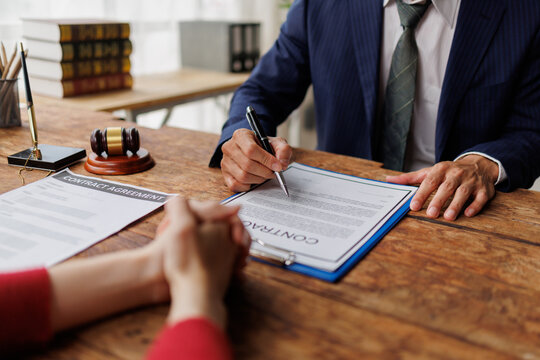 Legal professional consulting with client, explaining contract agreement terms, and providing guidance on important clauses during an office meeting