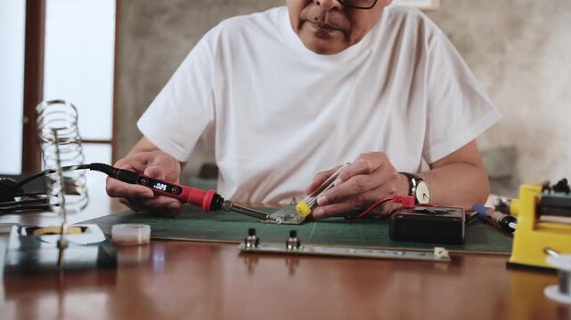 Close-up, man's hand repairs home electrical appliance, disassembling and soldering circuit board, focusing on precision detail, DIY fix tools, electronics component workshop hobby, expert handyman.