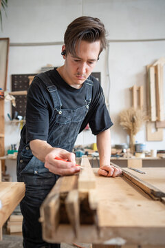 Qualified master restorer preparing patch for old window frame at workbench in restoration studio, concentrated carpenter drawing perfect line with pencil on wooden board, makes marks for detailed fit