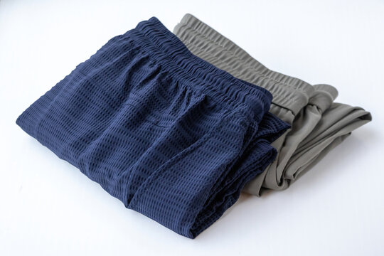 Stacked blue and olive grey men jogger trousers resting on clean background. Breathable casual activewear suitable for gym workout, running, and loungewear.