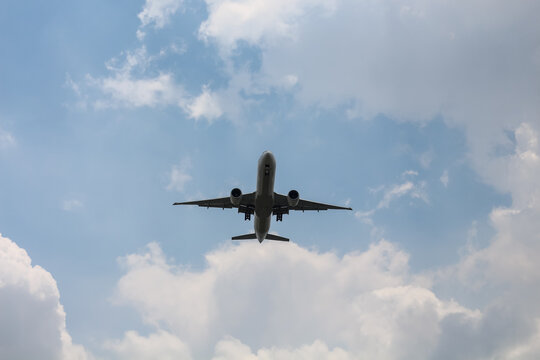 Commercial airplane flying overhead against a cloudy blue sky