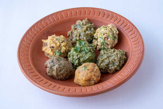 Assorted Bangladeshi mashed bhorta dishes including aloo, begun, chepa shutki, kachki fish, egg, borboti, and dal served in a traditional clay plate.