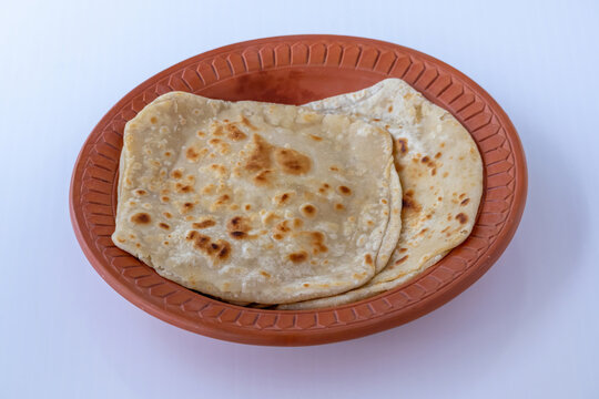 Soft Flaky Paratha Flatbread, Homemade Bangladeshi Style Breakfast Meal, Freshly Cooked Whole Wheat Roti Chapati on Clay Bowl, South Asian Cuisine.