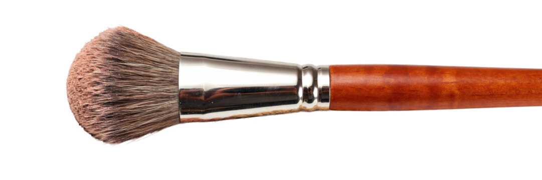 Cosmetic makeup brush resting on a pile of crushed beige and peach face powder isolated on a transparent background