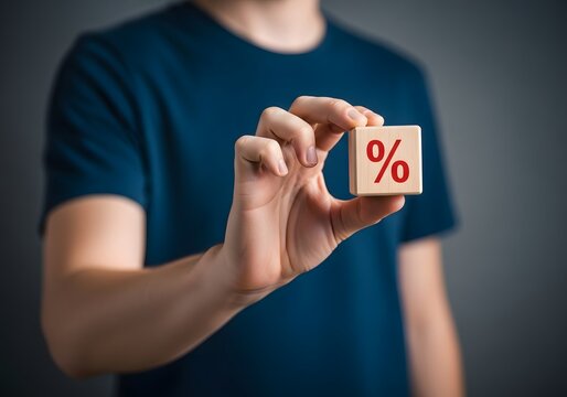 Person holding a single wooden cube with a red percentage symbol against a dark grey background