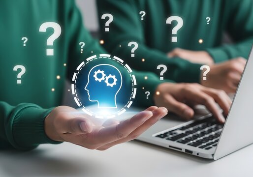 Person holding glowing head icon with gears and question marks while working on a laptop computer