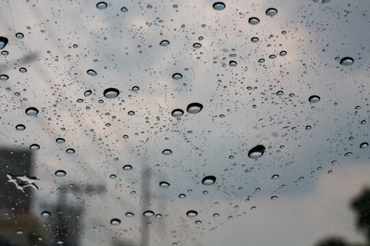 Raindrops on a window pane creating abstract patterns against a cloudy sky