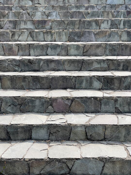 Full frame view of rustic stone stairs. Sharp focus reveals rough-cut slate textures and subtle mineral tones under soft natural light. Ideal for background texture, architecture mockups.