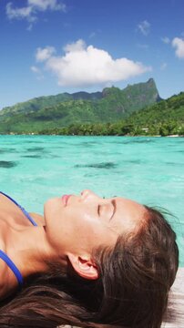 Skin care beauty and sun protection woman sun bathing by perfect water ocean beach. Close up of face. Multicultural mixed race model. Raw unedited vertical video of real woman model without any makeup