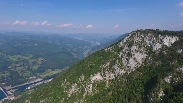 Aerial view of the rocky cliffs of Banjska Stena overlooking the Drina River valley with lush green forests and winding water in Rastiste, Zlatiborski okrug, Serbia.
