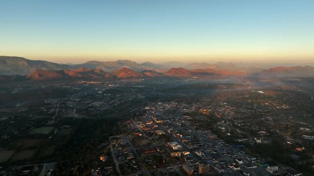 Golden hour aerial panorama of Mutare, Zimbabwe city in foggy valley