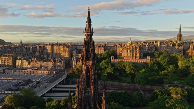 Aerial view of the historic Scott Monument surrounded by lush greenery and the urban skyline of the city during golden hour in Edinburgh, Scotland, United Kingdom.