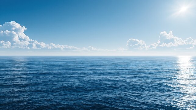 Calm deep blue open ocean with small gentle ripples under bright blue sky with fluffy white clouds and shining sun peaceful beautiful natural seascape scene