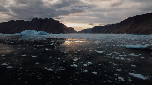 Drifting ice fills Franz Josef Fjord in Greenland beneath mountains at sunset.