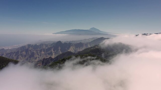 Aerial view of Mount Teide rising above a sea of clouds over the mountainous landscape of Santa Cruz de Tenerife, Canary Islands, Spain.
