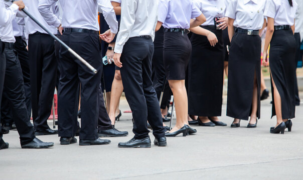 Lower body view of university students standing outdoors wearing black and white formal uniforms. Suitable for concepts of education, campus life, youth, and student community.