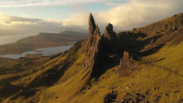 Aerial view of the Old Man of Storr rock formation with grassy slopes and golden hour light on the Isle of Skye in Highland Council, Scotland, United Kingdom.