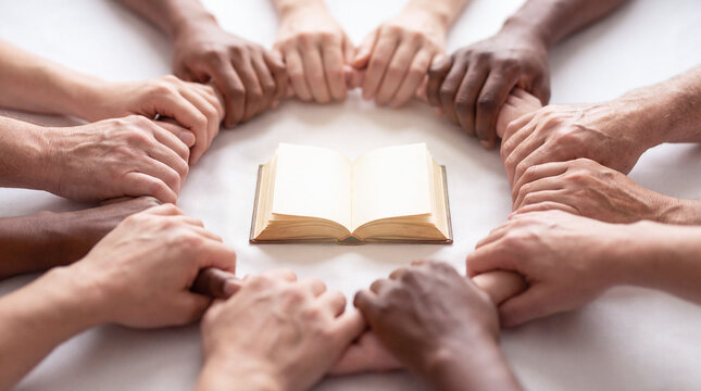 Diverse hands surrounding an open book representing unity and global community cooperation