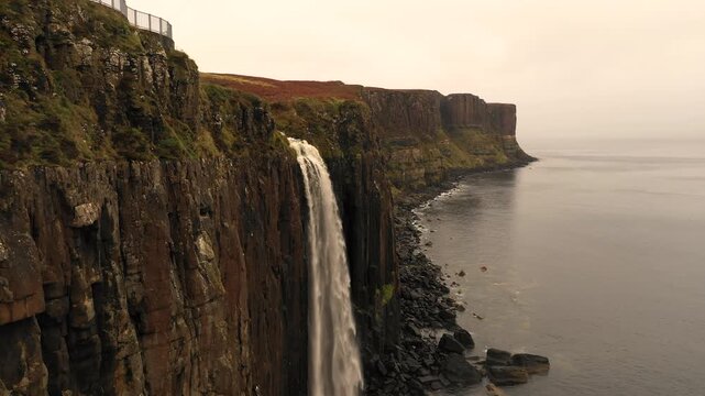 Aerial view of Kilt Rock waterfall cascading over basalt cliffs into the sea at Highland Council, Scotland, United Kingdom.
