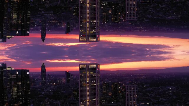 Aerial view of a mirrored city skyline with illuminated skyscrapers against a vibrant sunset sky in the United States.