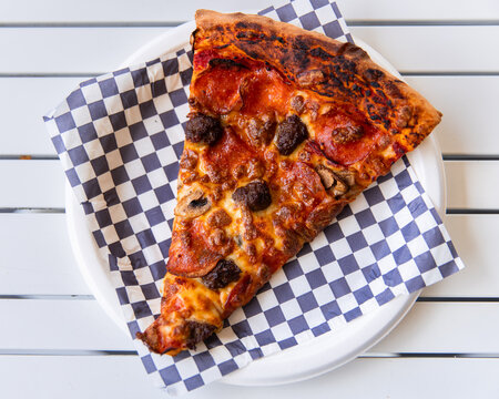 slice of pizza with mushroom and pepperoni on a paper plate