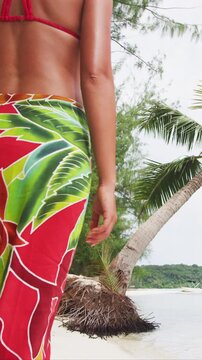 Polynesia Travel woman walking on paradise beach on holidays vacation on Matira Beach, Bora Bora on holidays vacation in traditional pareo and in Tahiti, French Polynesia. Vertical video of real woman