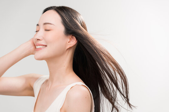 笑顔の日本人女性の長く美しい髪が風になびいている　