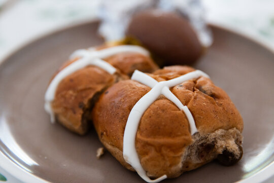 hot cross buns on a plate with an easter egg in the background