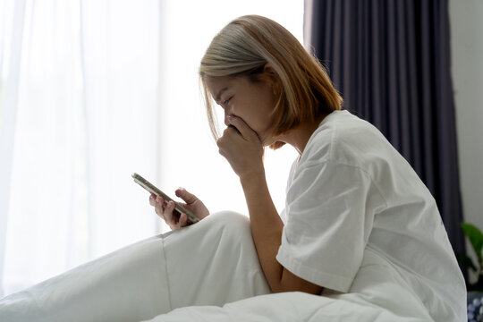 Depressed and stressed Asian woman looks at her smartphone. Negative emotions and concepts regarding mental health.