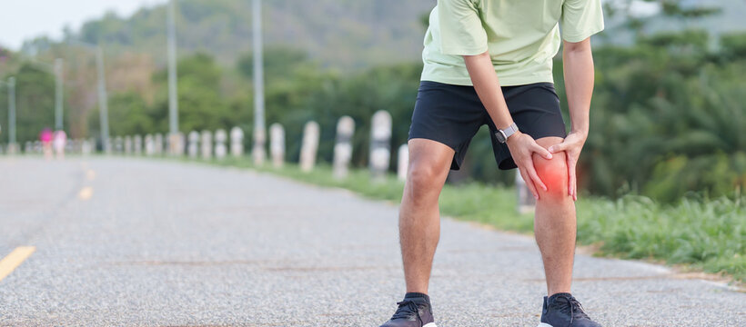 Young adult male runner with knee pain from ACL injury or patellofemoral syndrome. Man having joint ache, ligament tear or patellar tendinitis during running. Sports medical and healthcare concept
