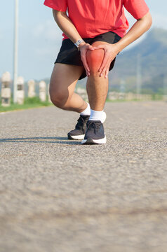 Young adult male runner with knee pain from ACL injury or patellofemoral syndrome. Man having joint ache, ligament tear or patellar tendinitis during running. Sports medical and healthcare concept