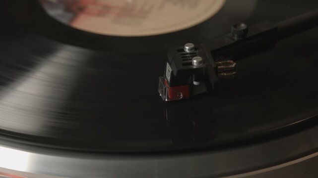 Close up of record player needle on spinning vinyl record playing music, offering nostalgic and vintage audio experience.