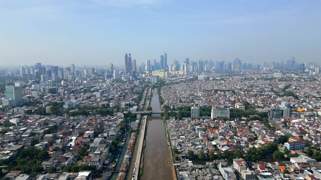 Aerial view of Jakarta skyline with dense urban housing and river cutting through the city. Wide cityscape showing scale, infrastructure and metropolitan life in Indonesia.