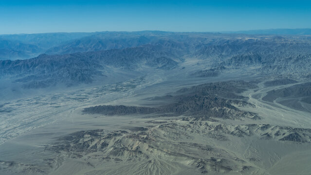 Desert landscape. A view from above, from an airplane. Lifeless mountains, devoid of vegetation, sand dunes. Blue sky. Peru. Nazca Plateau.