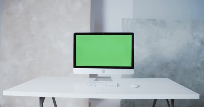 Modern computer monitor with blank green screen mockup on white minimalist office desk