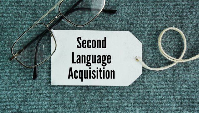 Glasses and paper tags with the words Second Language Acquisition. the process by which people learn an additional language after their first or native language is already established.
